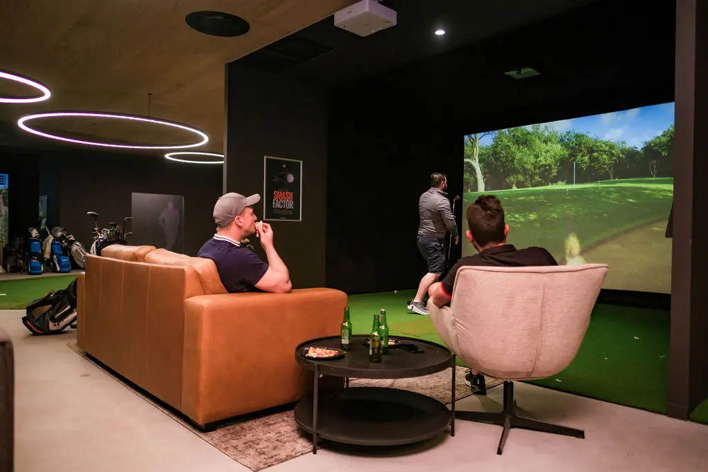 Group of men playing Trackman virtual golf while enjoying beers and pizza at Par 72, located in Pretoria, South Africa.